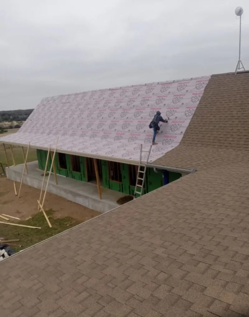 Worker preparing underlayment for a metal roof installation in Salem